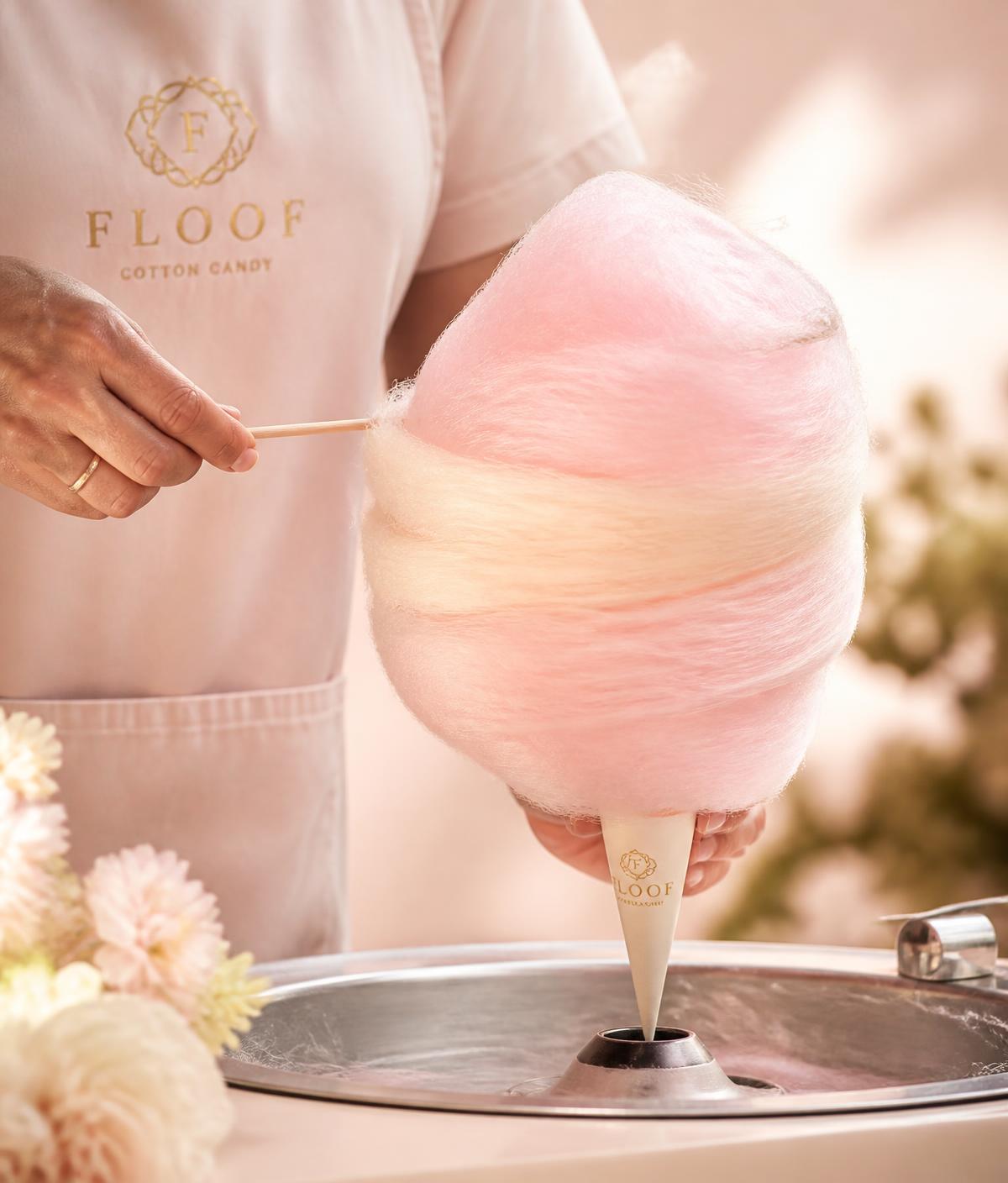 A pastel cotton candy cone being spun by hand