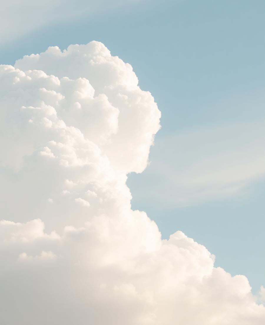 Fluffy white clouds in a pastel blue sky